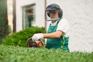 Man wearing ear and face protection using trimming machine